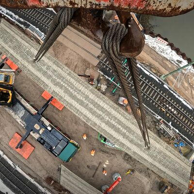 Vogelperspektive auf einen Stahlträger an einem Mobilkran, am Boden Gleise.