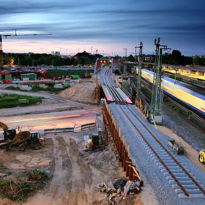 Abendliche Baustelle an Eisenbahnstrecke, daneben Gleise und ein Bahnsteig.