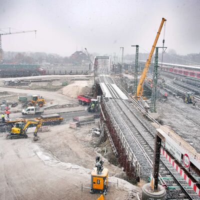 Winterliche Baustelle an einer Eisenbahnstrecke mit Baumaschinen.