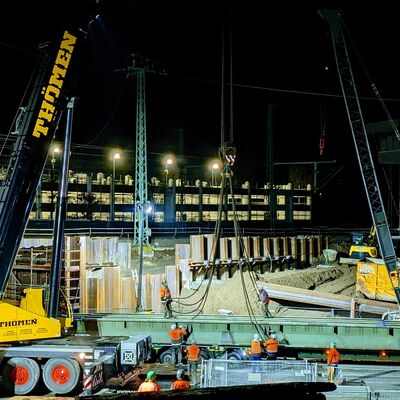 Hilfsbrücke wird bei Nacht mit Mobilkran von einem Schwerlasttransporter gehoben.