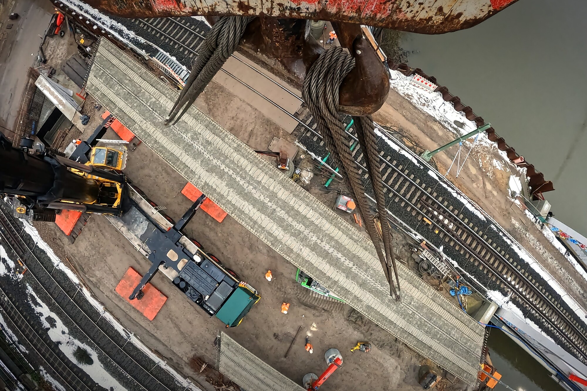 Vogelperspektive auf einen Stahlträger an einem Mobilkran, am Boden Gleise.